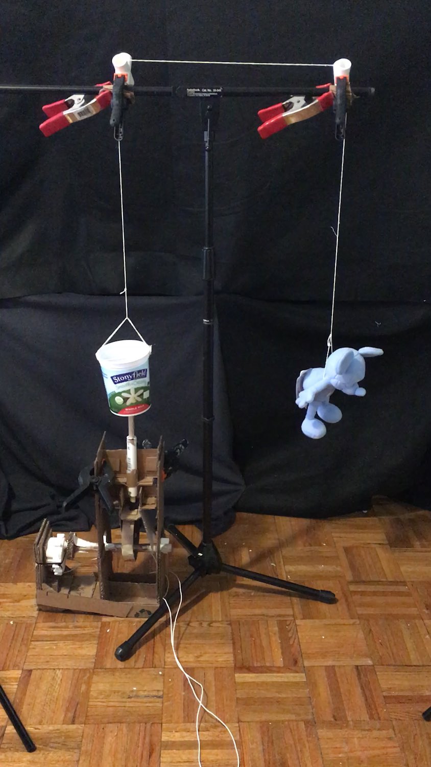 A stuffed Mickey Mouse hanging from a string, attached to a cam mechanism