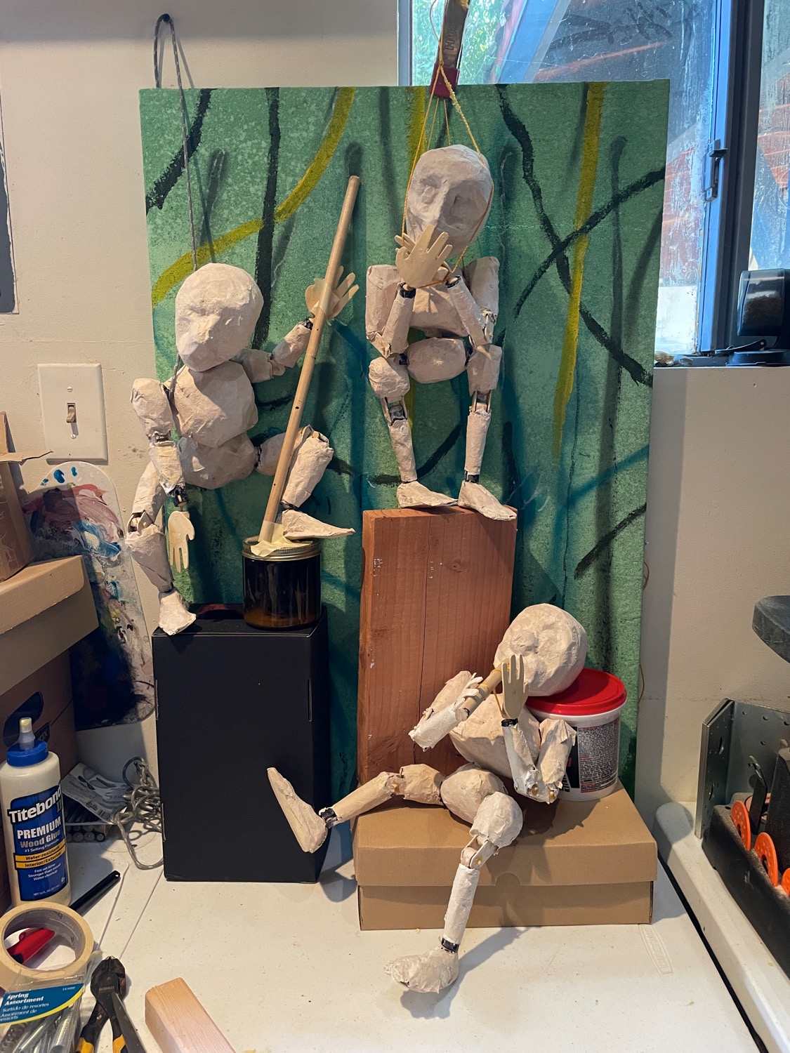 The three sculputed characters in a vertical composition, all sitting or standing at different heights and focused on their placeholder instruments