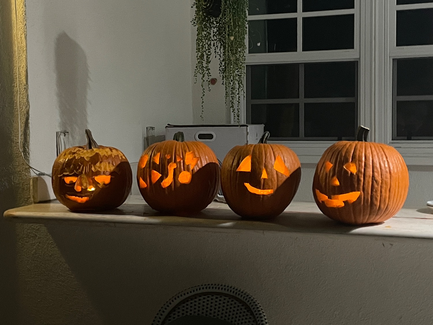Four carved pumpkins sitting in a row on a counter. One has eyebrows.