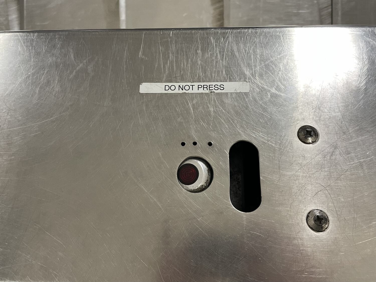 A button on a nondescript metal panel labeled 