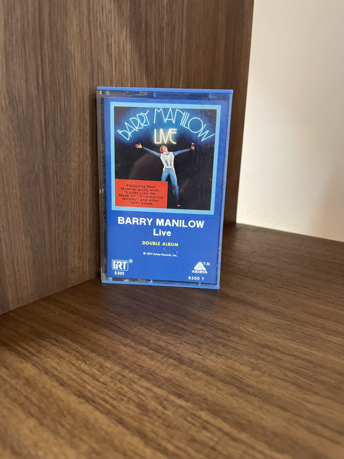 A Barry Manilow Live cassette sitting on a shelf