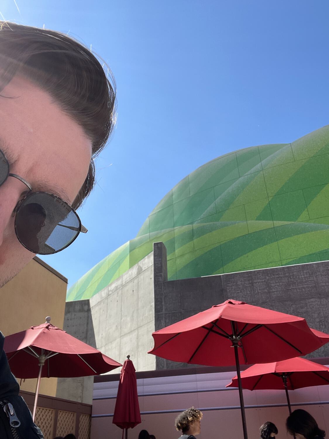 A selfie with the under-construction green hills of Super Nintendo World in the background