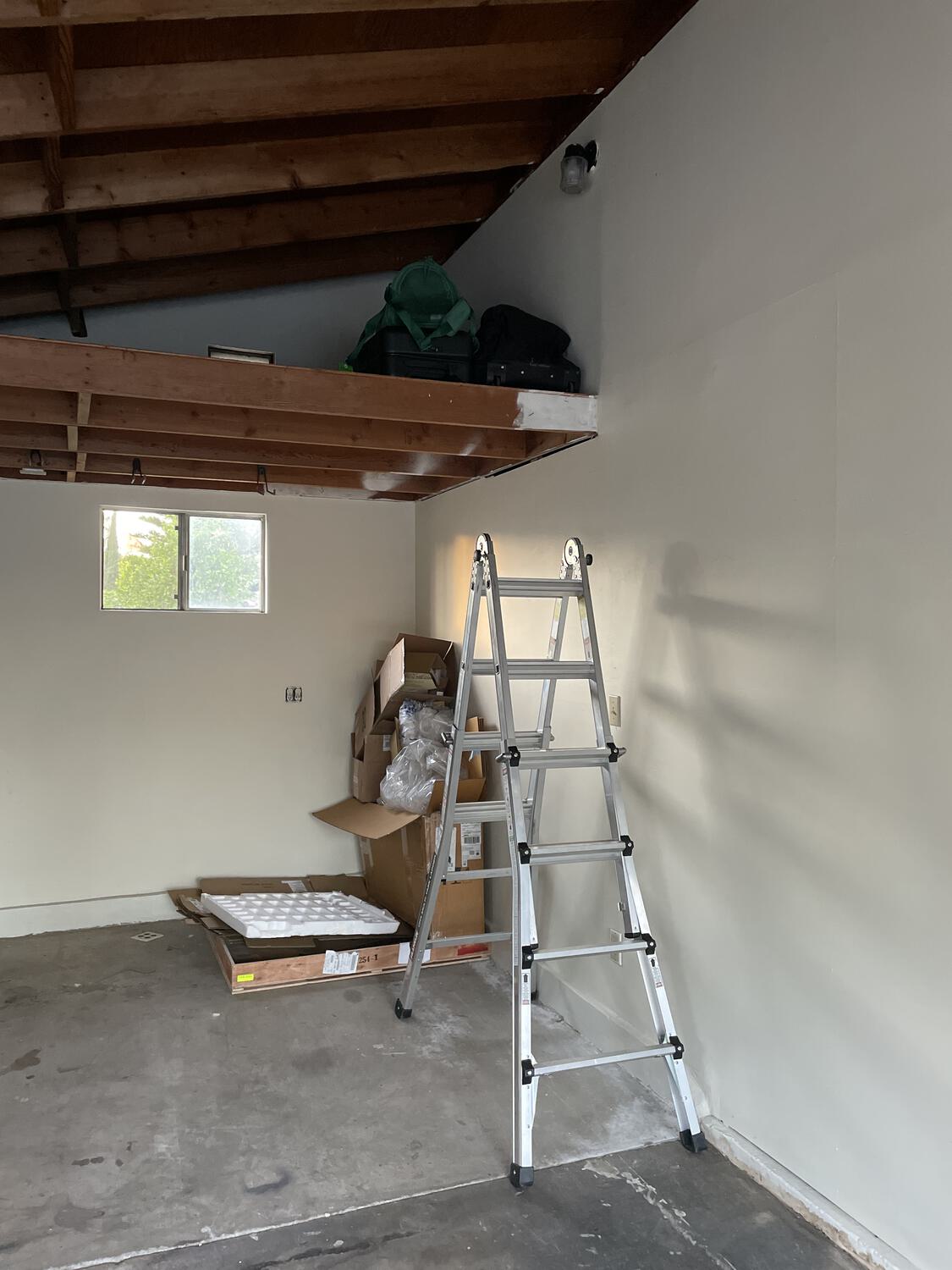 A ladder leading to a mostly-empty loft in a mostly-empty garage