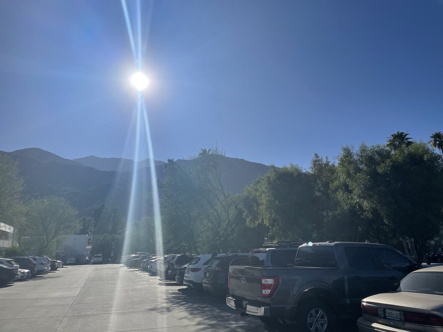 Mountains and a bright sun as seen from a parking lot