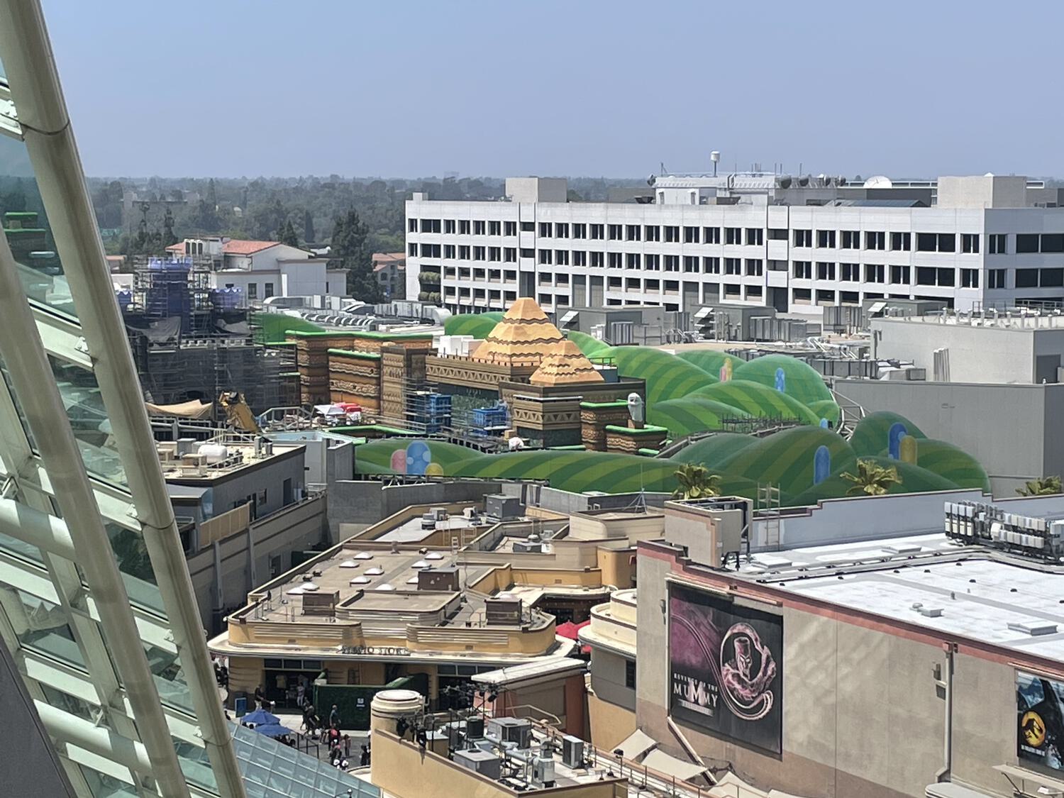 A very distant overhead shot of green cartoon hills rising among soundstages