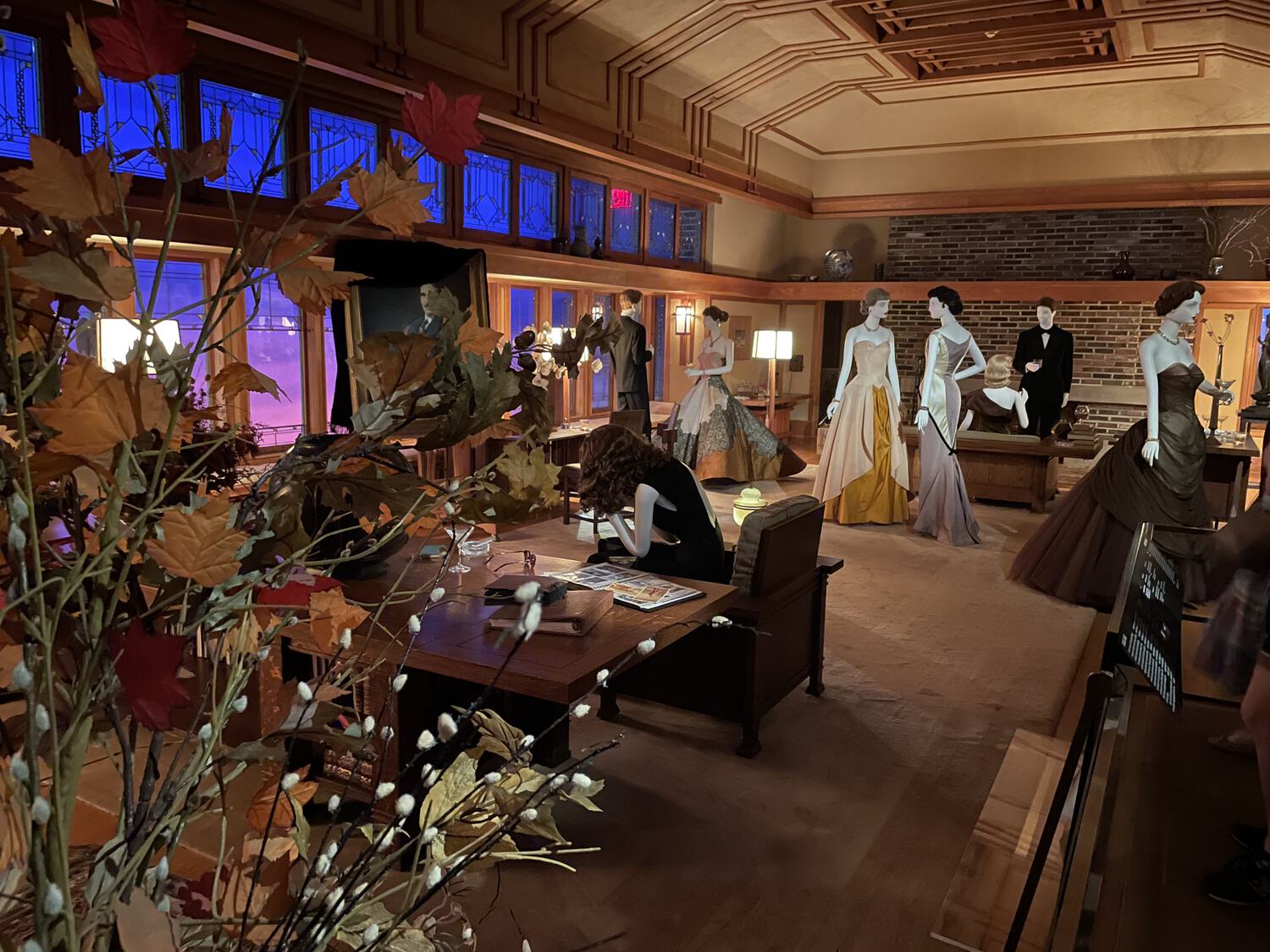 Mannequins dressed in mid-century formalwear, scattered dramatically around a living room designed by Frank Lloyd Wright