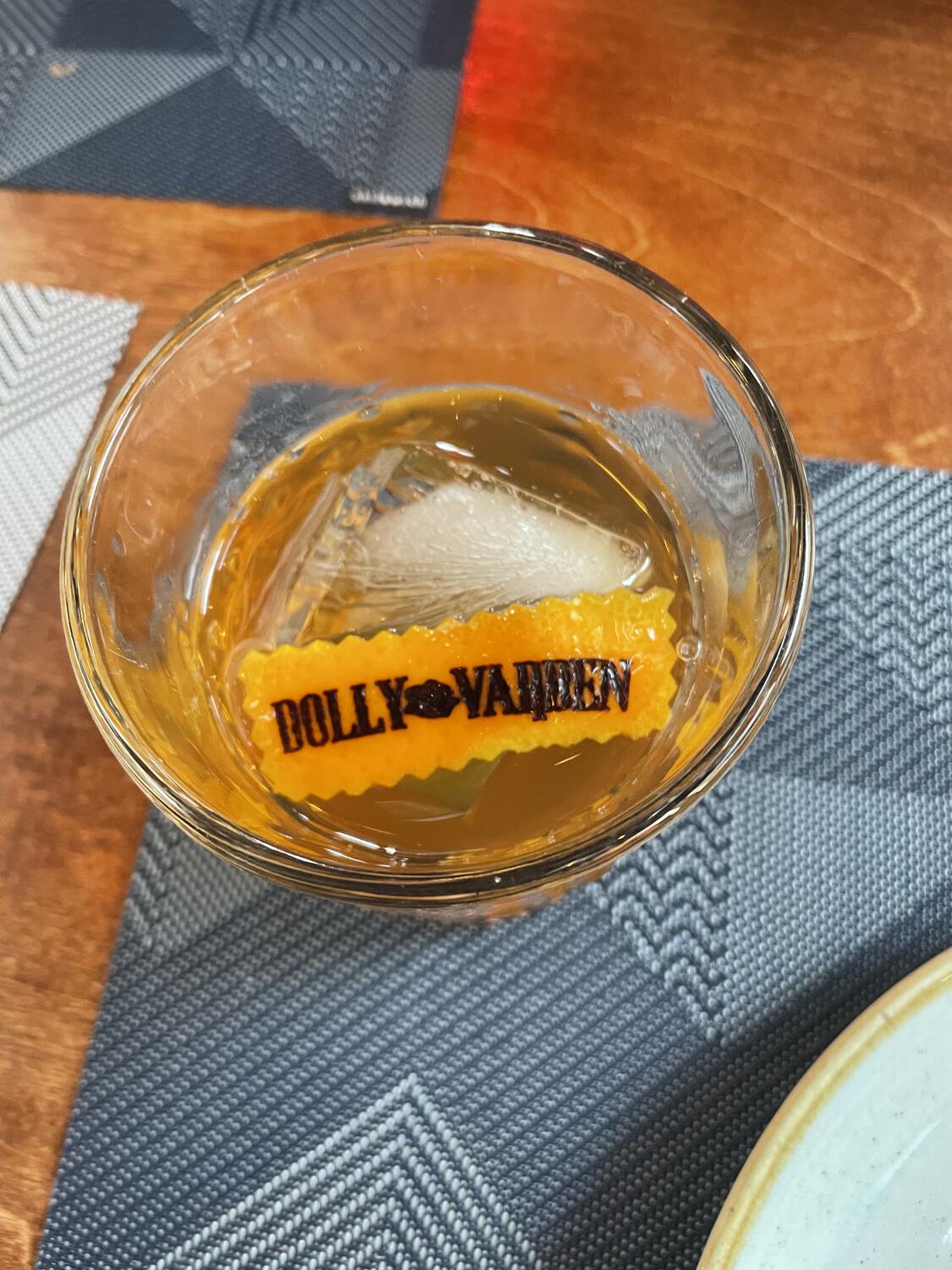 An orange slice in a cocktail with "Dolly Varden" branded on it