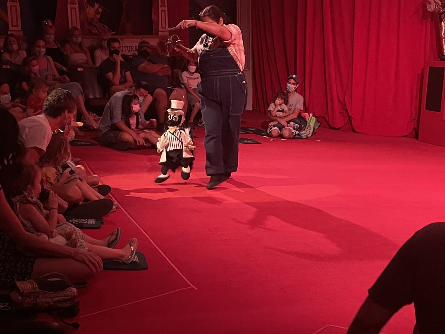 A marionette of a skunk in a fine suit, performing for children in a small theater