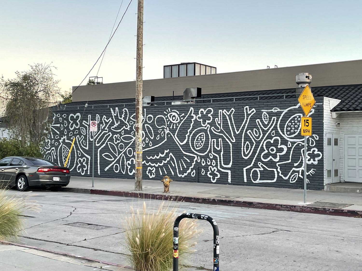 A mural from across the street. Bold white illustrations on a black brick wall.