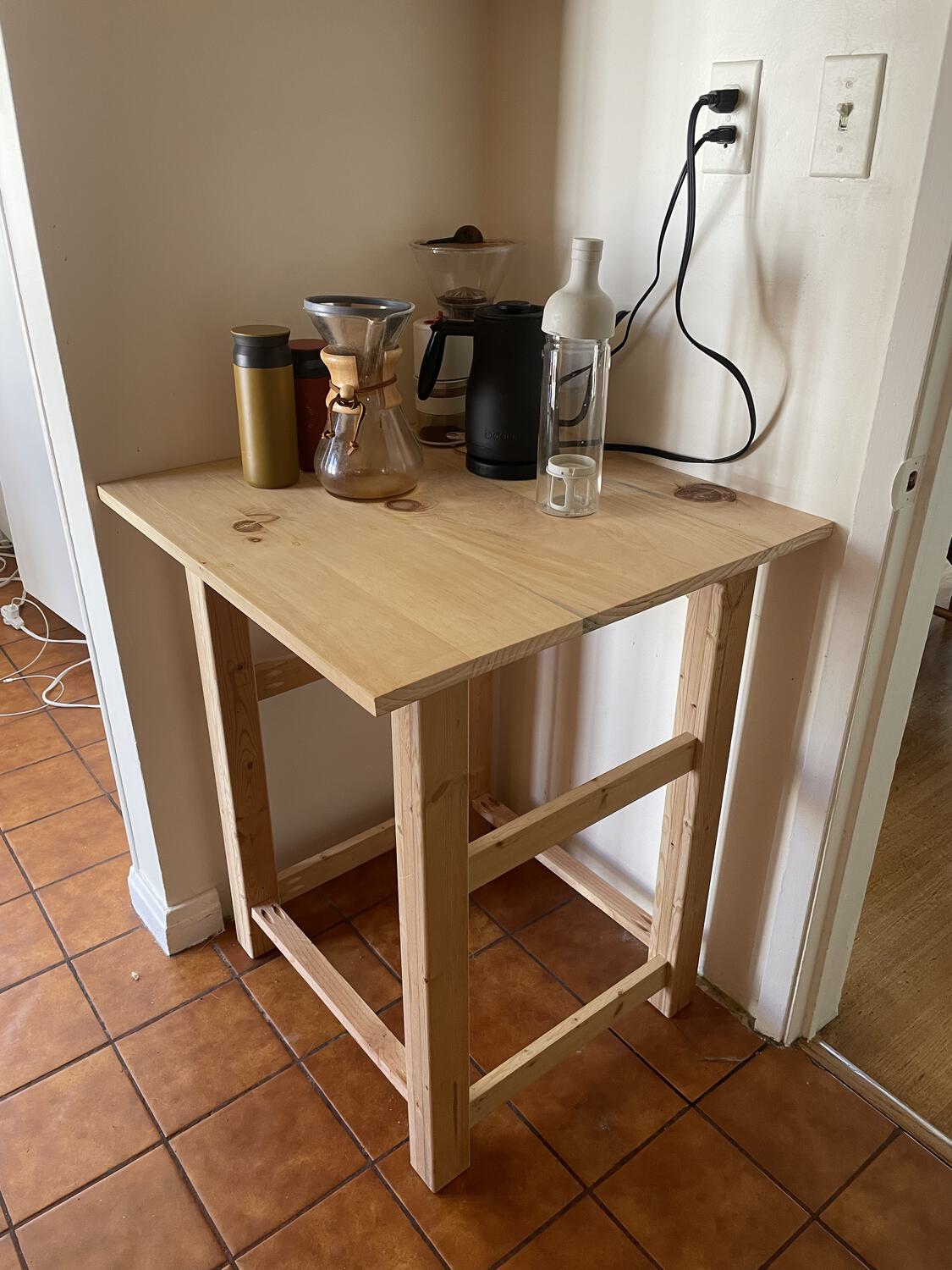 A simple wooden table with coffee accessories atop it