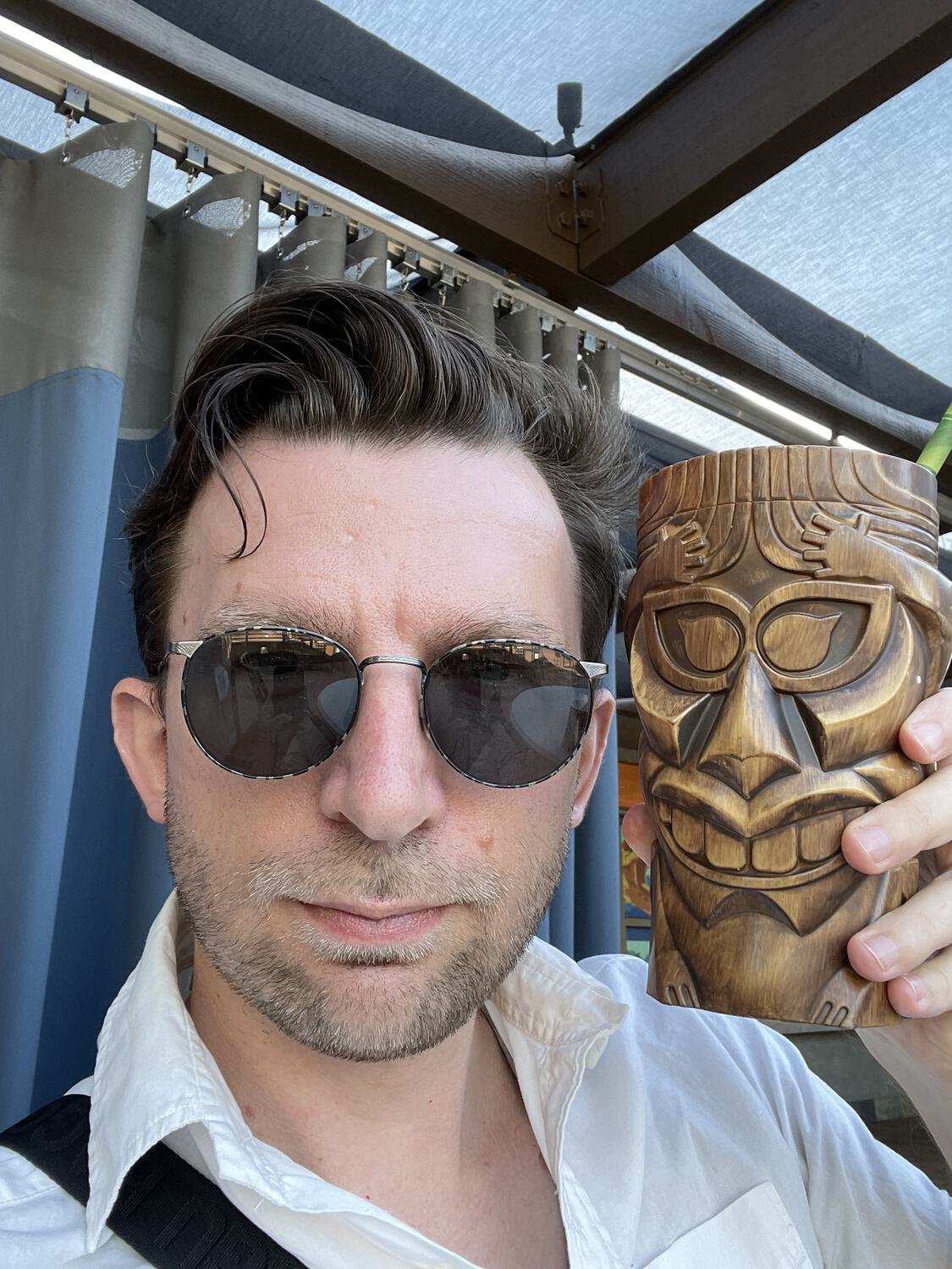 A selfie showing the size of a faux-wood Tiki mug. It's almost the size of my head.