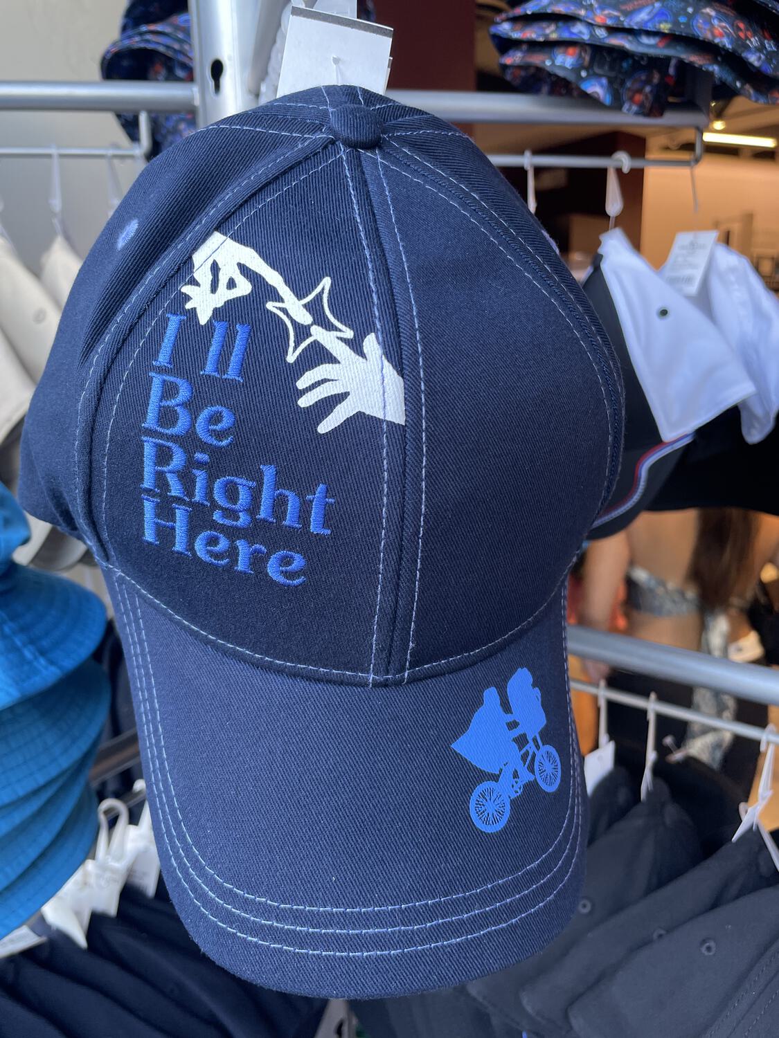 A baseball cap that reads "I'll Be Right Here," with imagery depicting E.T. and Elliott