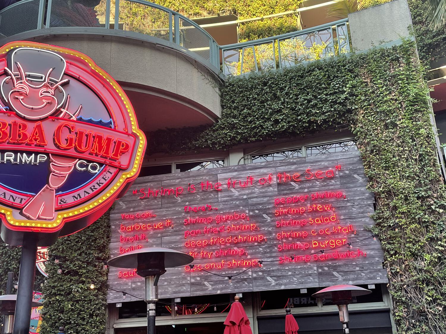 A neon sign above the Bubba Gump entrance that recites the quote from Forrest Gump enumerating all the ways to prepare shrimp