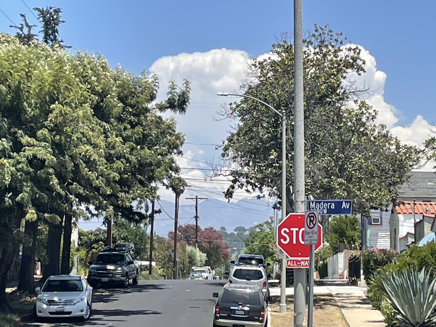A bucolic Los Angeles street with puffy clouds and mountains in the background