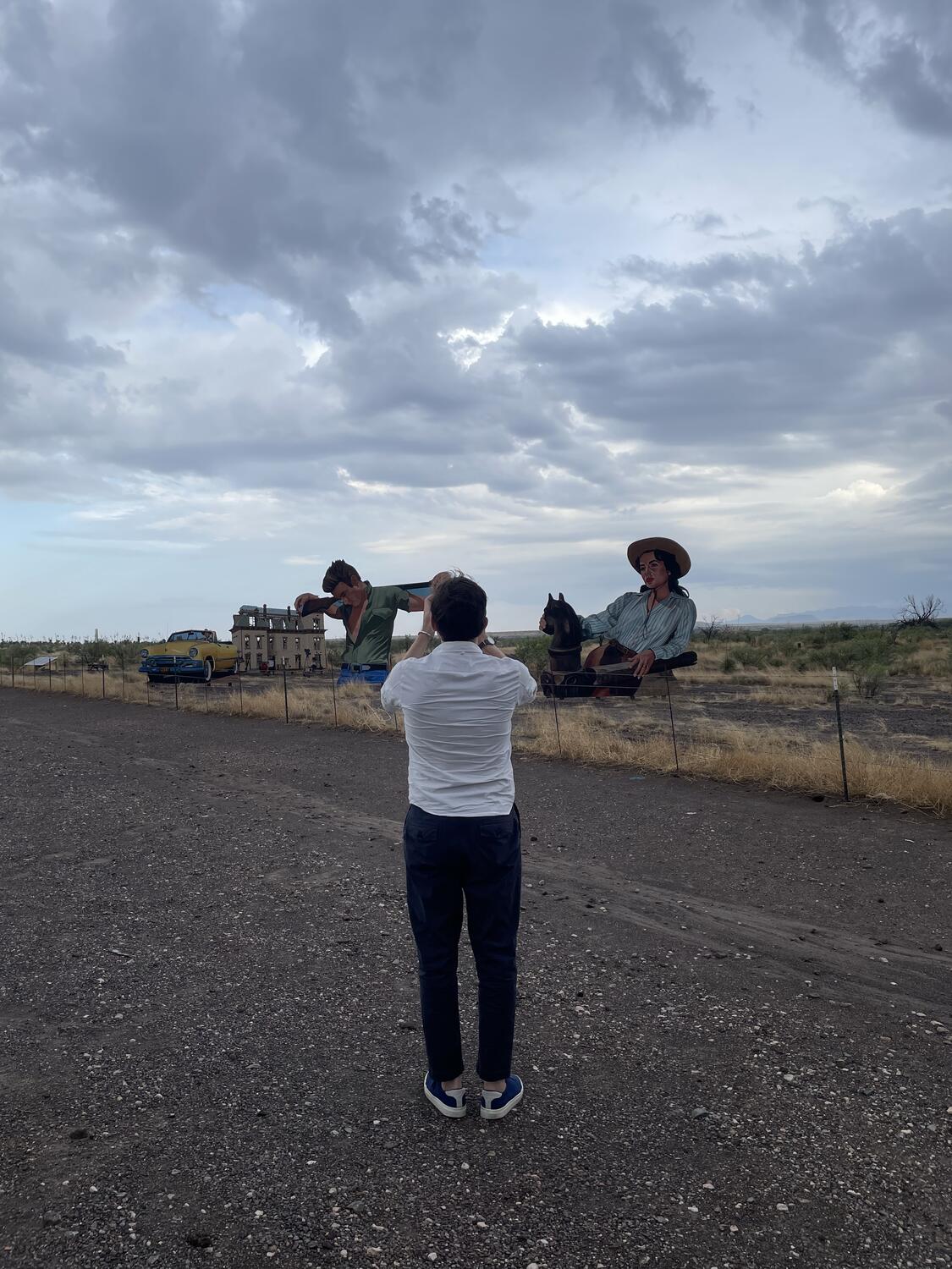 A photo of me from behind, taking a photo of huge plywood figures depicting the characters in the movie Giant