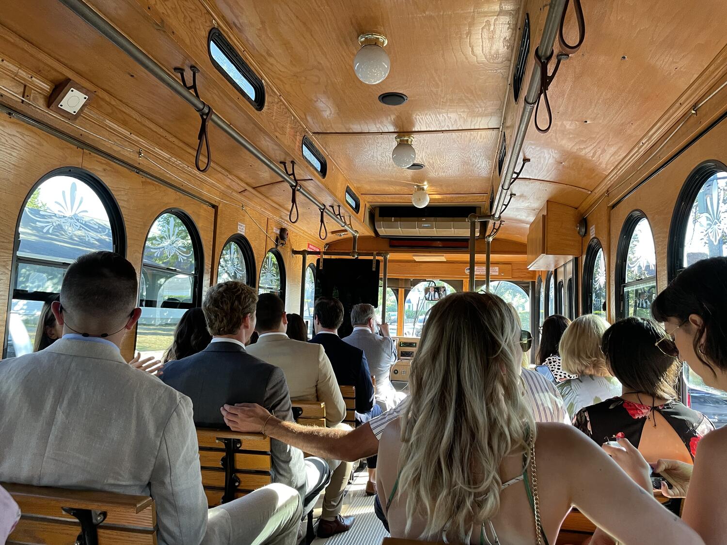 A classic trolley full of well-dressed wedding guests, seen from the rear so it's the backs of everyones' heads