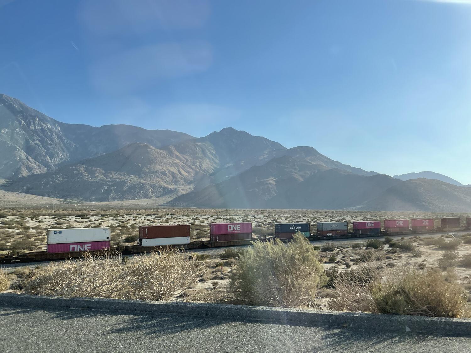 A train filled with shipping containers chugs along beside the mountains toward (or away from?) Palm Springs