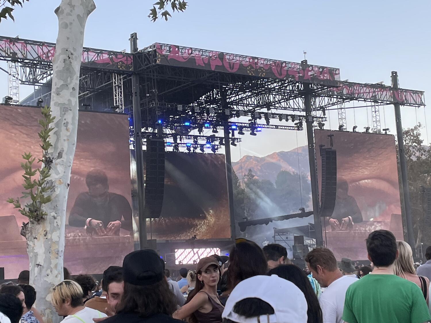 Kaytranada DJing on stage. We can hardly see him from this distance, but the big video screens flanking the stage give us a good view of him working a mixer.