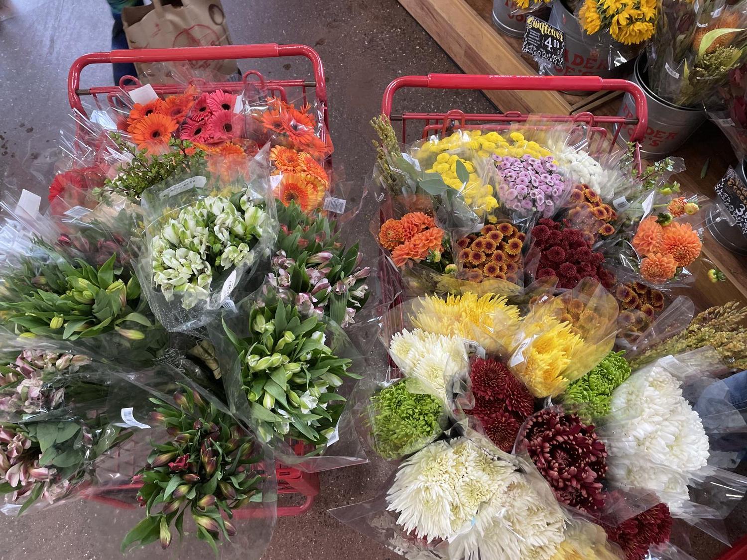 Two shopping carts overflowing with bouquets of flowers in mostly subtle Autumn colors