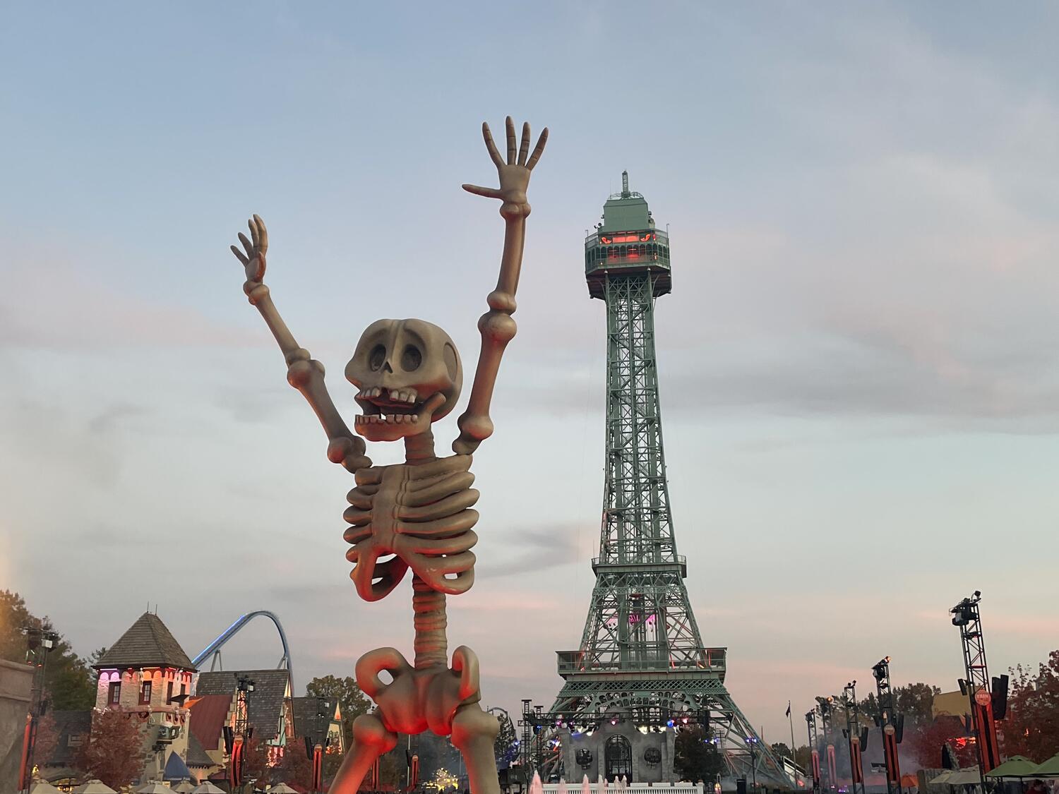 A big skeleton sculpture uplit by a red light. In the background is the Eiffel Tower, and further away there are the tips of some rollercoasters