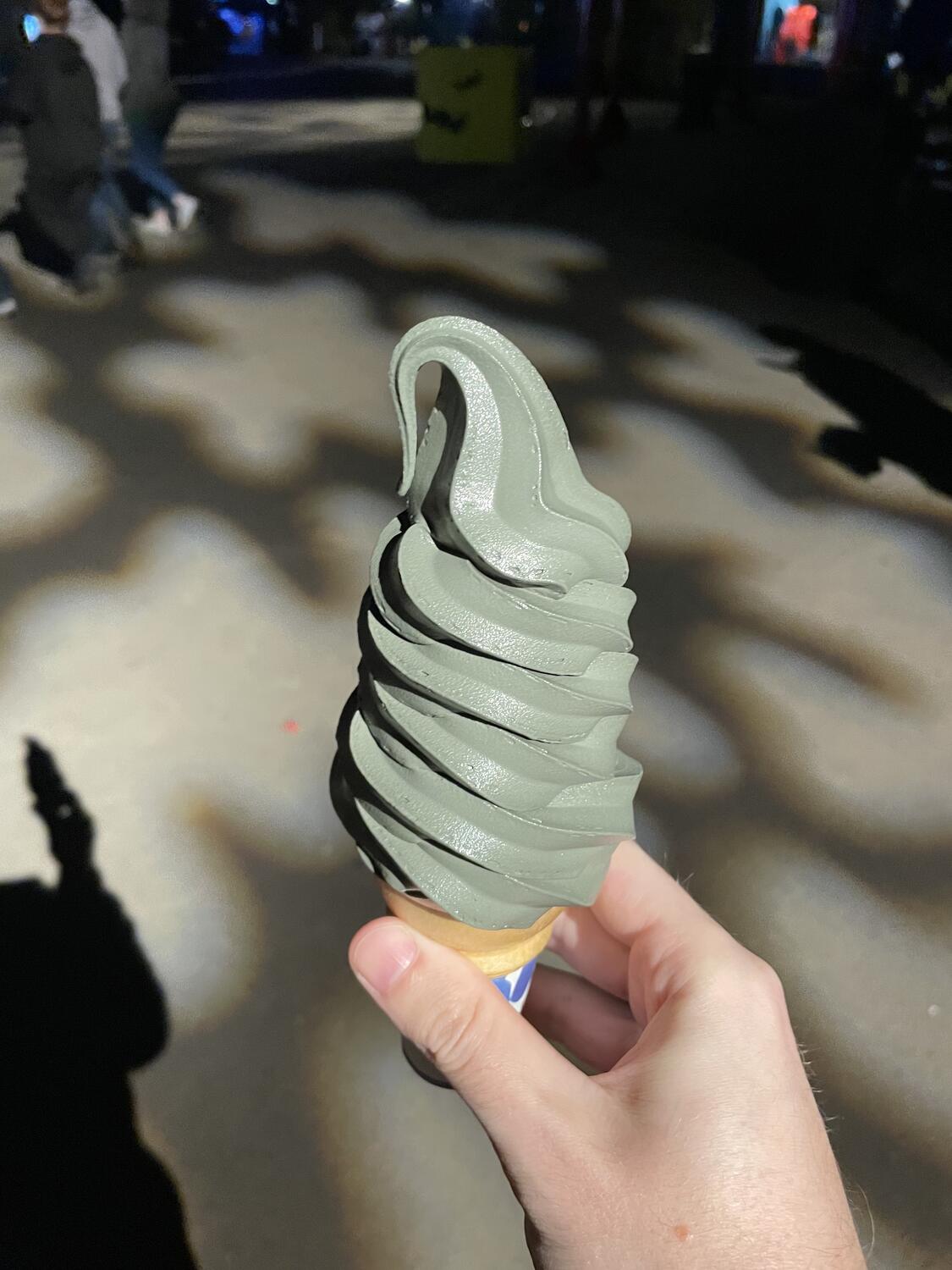 A soft-serve cone in an unsettling greying-green hue