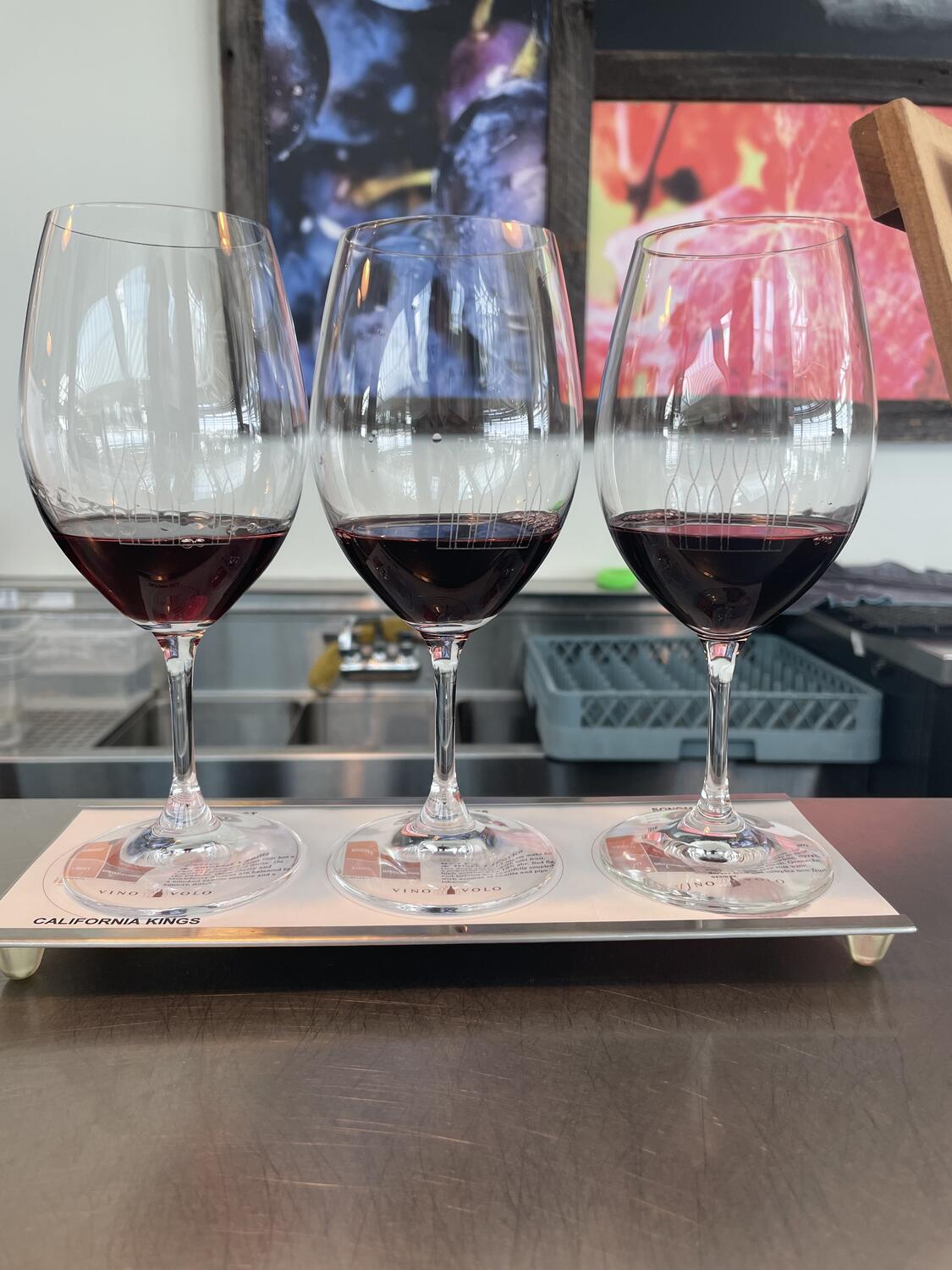 A flight of red wines at an airport bar