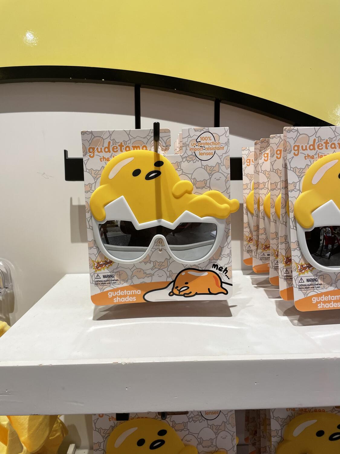 Sunglasses in the shape of Gudetama, the Sanrio character that is a fried egg. The lenses are the egg shell and Gudetama sits on your forehead.