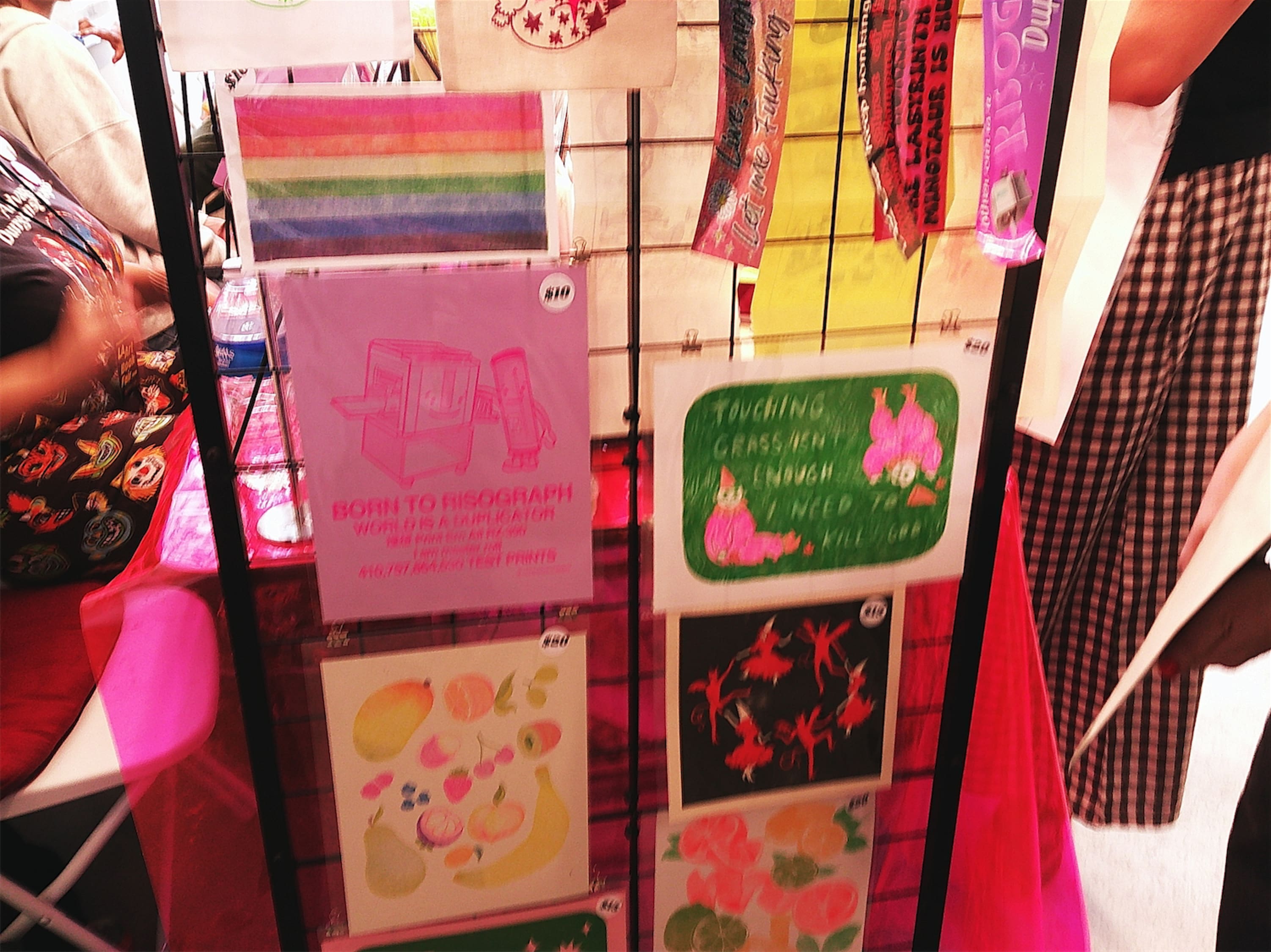 A bunch of prints clipped to a stand, including one that reads: BORN TO RISOGRAPH - WORLD IS A DUPLICATOR