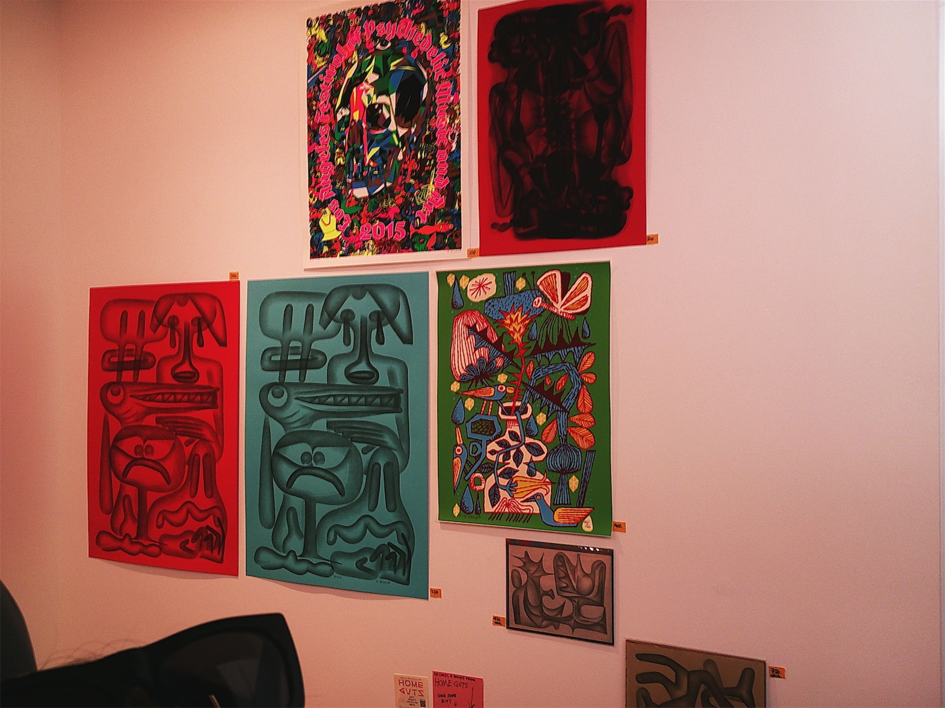 A few abstract prints pinned to a wall