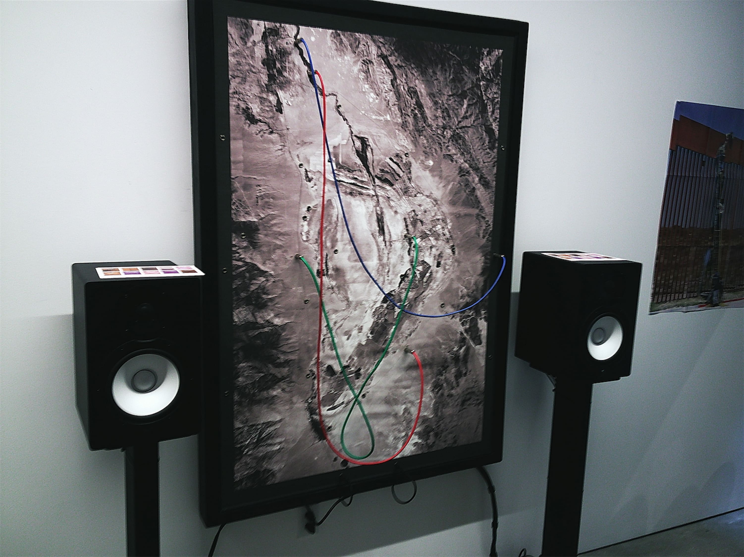 A large framed print of a topographic photo splattered with 1/4-inch plugs. Among them some are connected by thick cables in different colors.