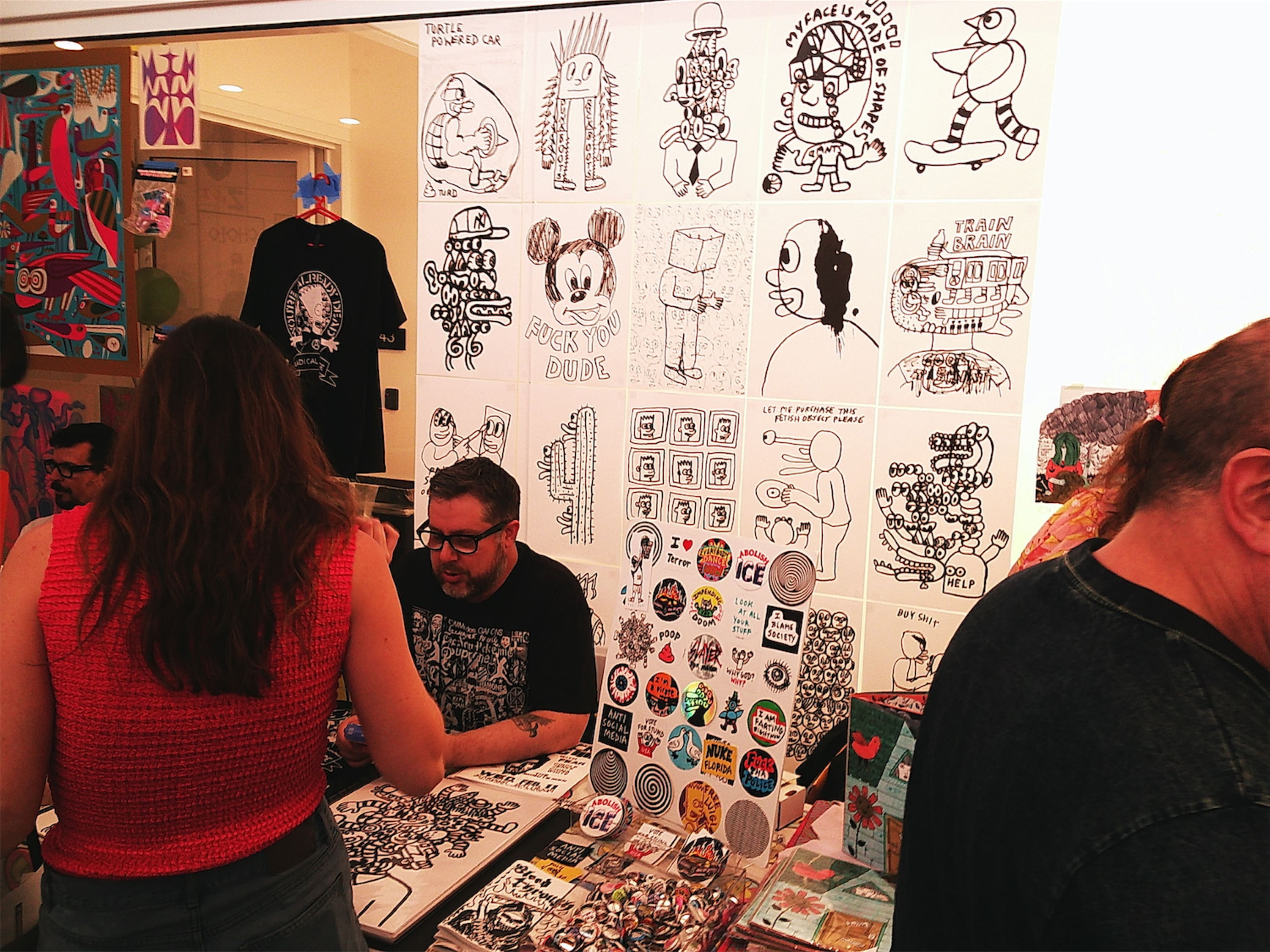 A vendor purveying handmade art in a bold, hand-to-marker style