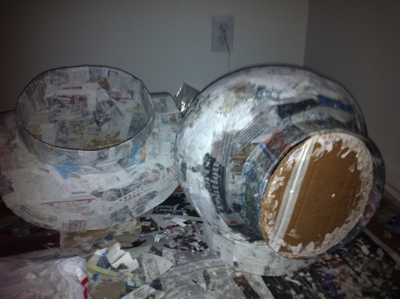 A blurry photo of some unidentifiable spherical objects made from papier mache. Wet newsprint and corrugated cardboard.